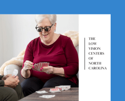 A smiling, silver-haired woman wearing bioptic telescope glasses playing cards with a friend